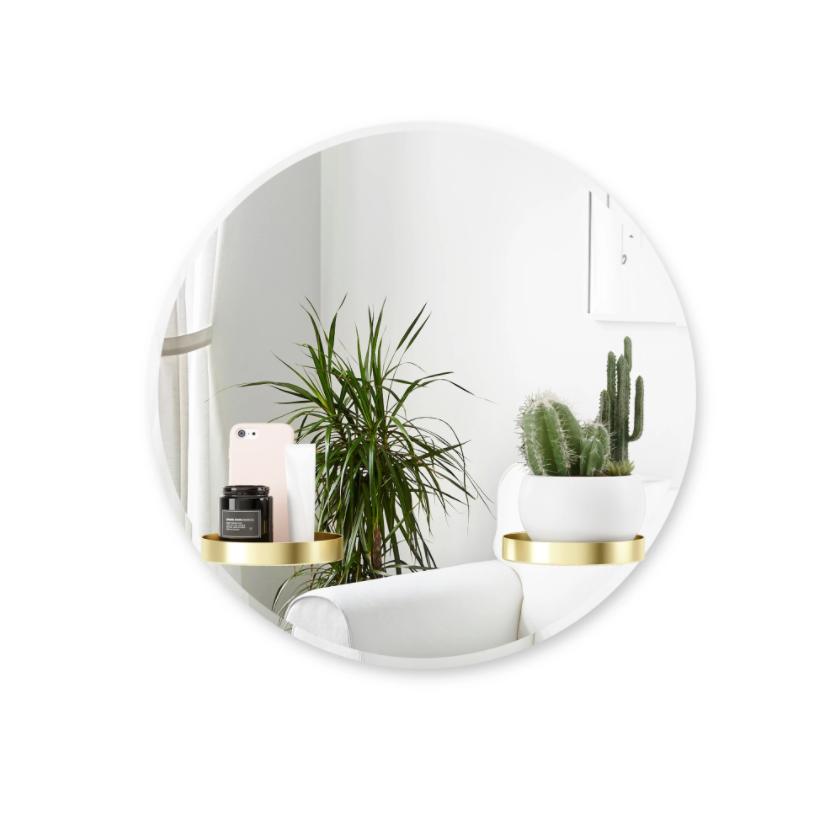 Umbra Perch round mirror with brass shelves holding plants and a bowl