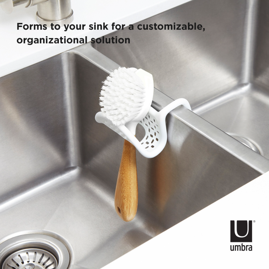 Umbra Sling sink caddy in white on a stainless sink, holding a brush and a wooden scrubber
