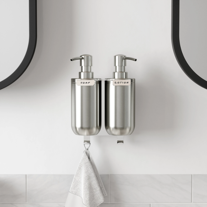 Umbra Junip wall soap pumps mounted beside a round mirror above a basin