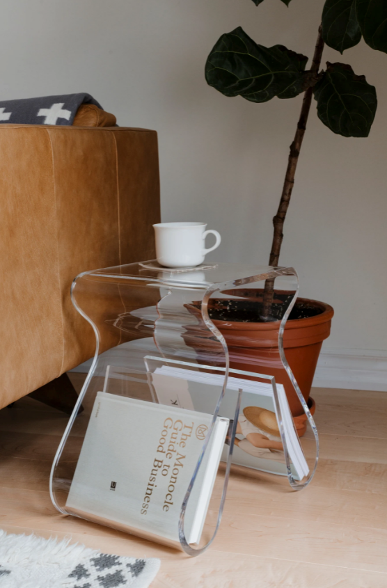 Magino stool by a leather chair and potted fig, a cup on top and a book in the rack