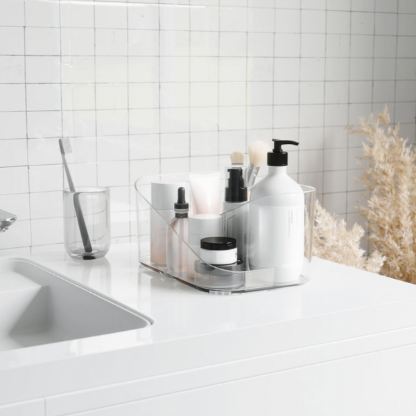 A white bathroom with a sink, mirror, and Umbra GLAM COSMETIC ORGANIZER - Clear soap dispenser.
