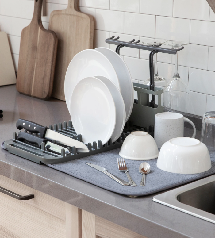Umbra Udry dish rack and microfibre mat beside a sink holding plates and cutlery