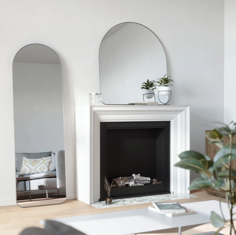 Umbra Hubba arched mirror in titanium above a fireplace beside a full length mirror