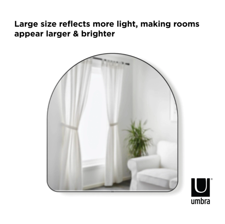 Umbra Hubba arched mirror in titanium reflecting a curtained window and chair
