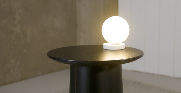 A black Yuri Table lamp with a lamp on it by Ned Collections.