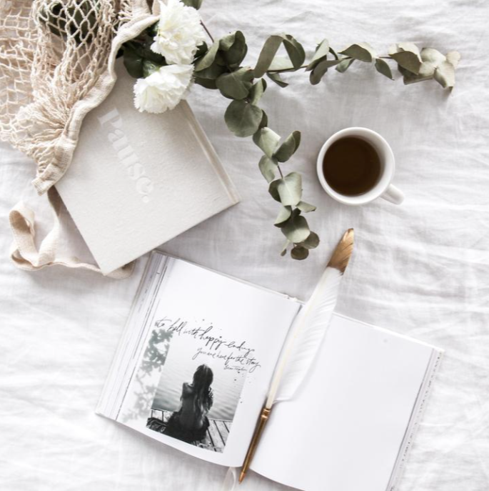 Overhead flatlay of the Coco feather pen with a journal, coffee cup and eucalyptus sprigs