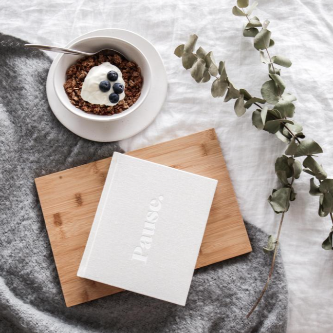 Press Pause journal on a timber board beside a bowl of granola and eucalyptus