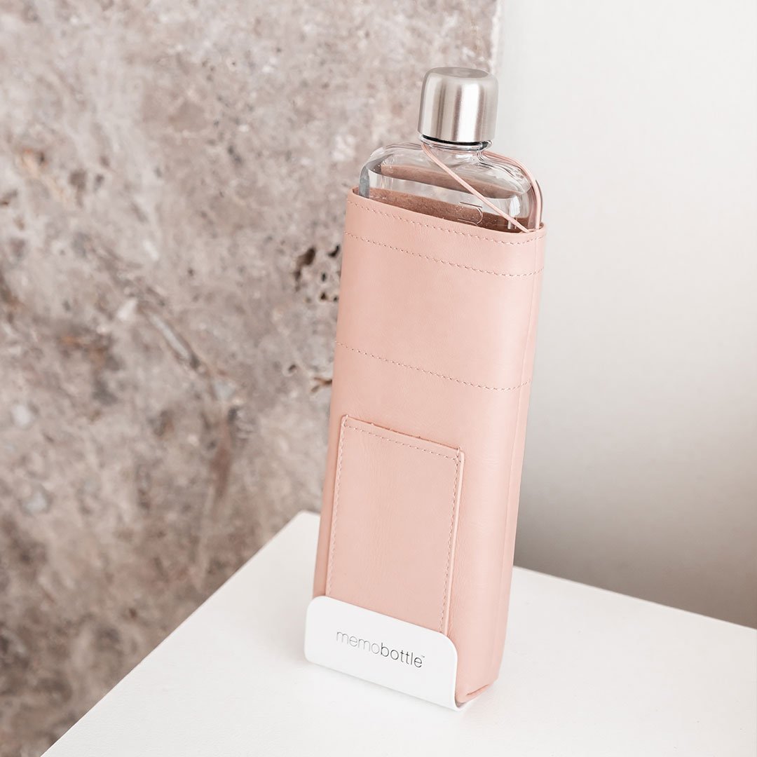 Memobottle in a blush leather sleeve held upright in a white desk stand