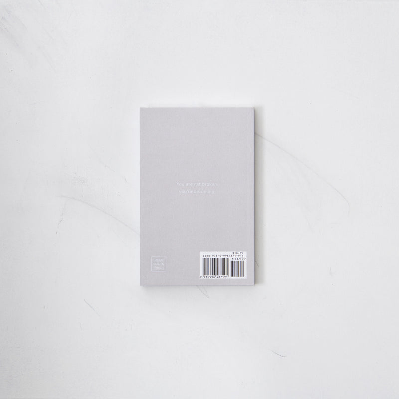 A white notebook from Thought Catalog's "The Strength In Our Scars" collection on a white surface.