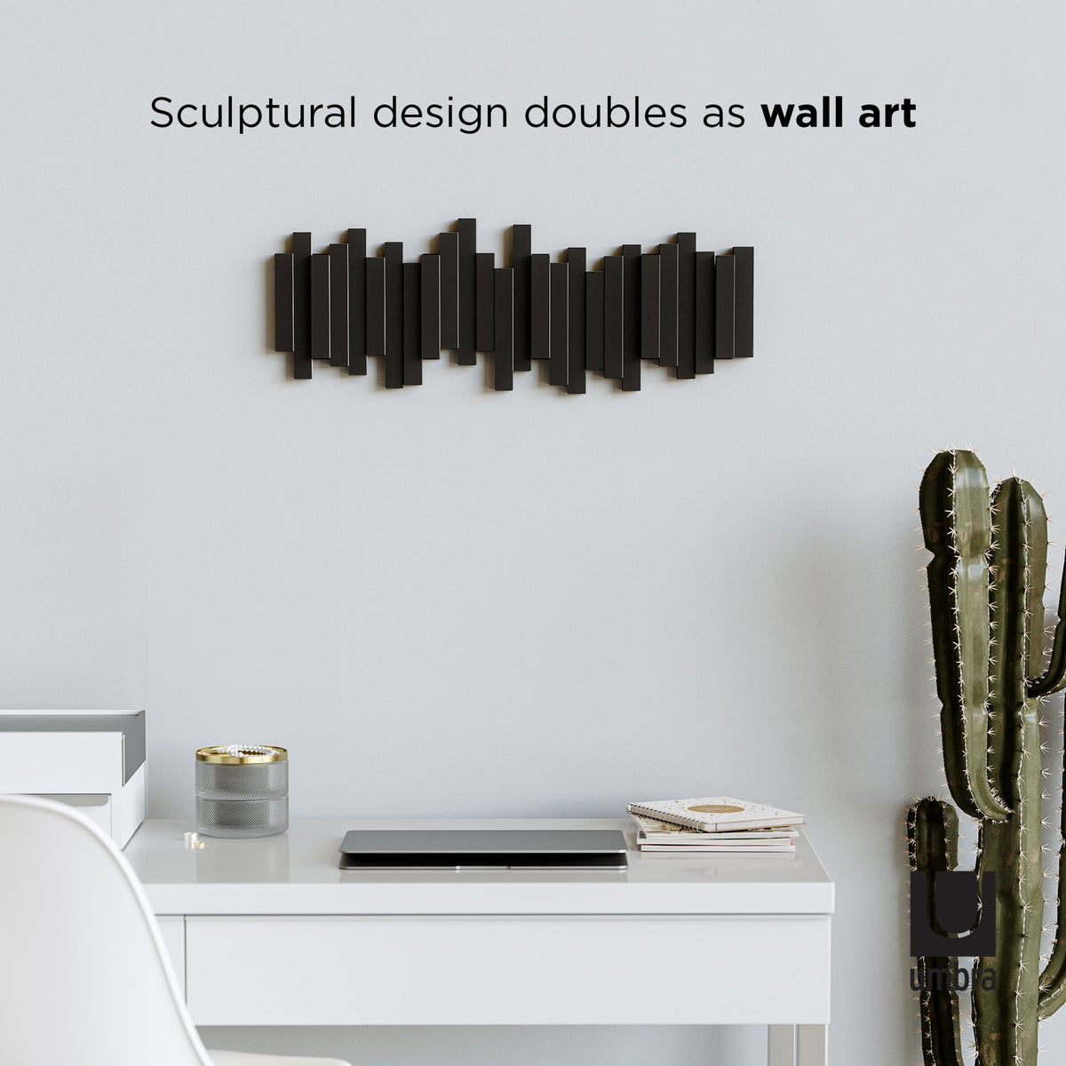 Umbra Sticks 5 hook rack in black above a desk, sculptural design that doubles as wall art