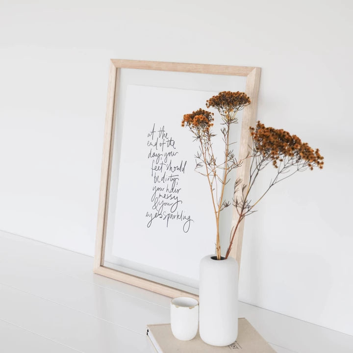 Framed Eyes Sparkling print beside dried flowers in a white vase