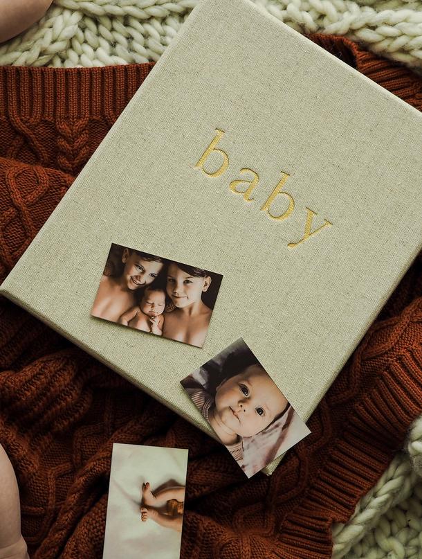 Oatmeal Write To Me baby journal with baby photos on a rust knit blanket