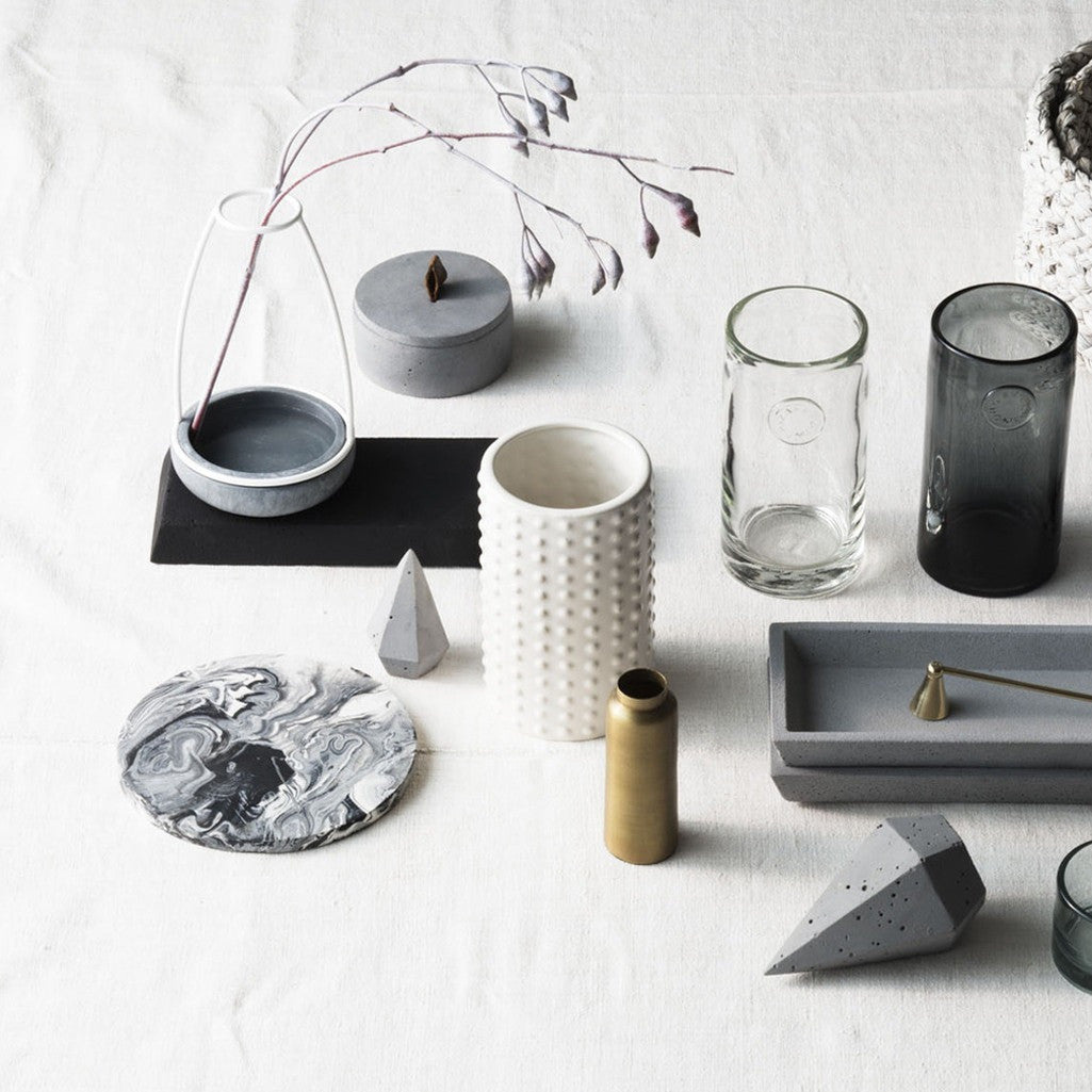 Flat lay of Zakkia concrete trays, dishes and vessels with glassware on a white surface