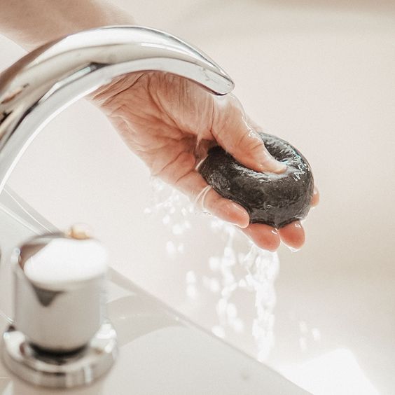A person deep cleans their pores while washing their face with Florence's KONJAC PREMIUM FACIAL PUFF SPONGE WITH BAMBOO CHARCOAL.