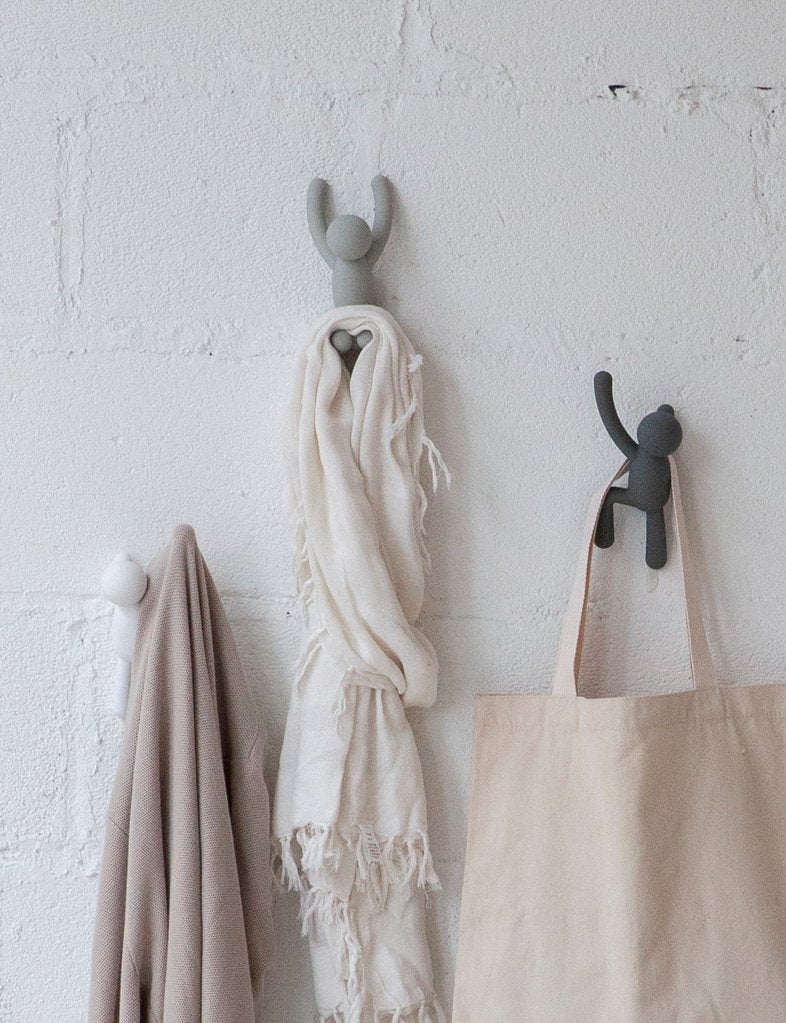 Umbra Buddy hooks on a brick wall holding a throw, robe and canvas tote