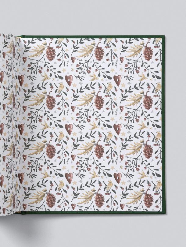 Christmas Family Book open to its illustrated botanical endpapers, with the forest green cover