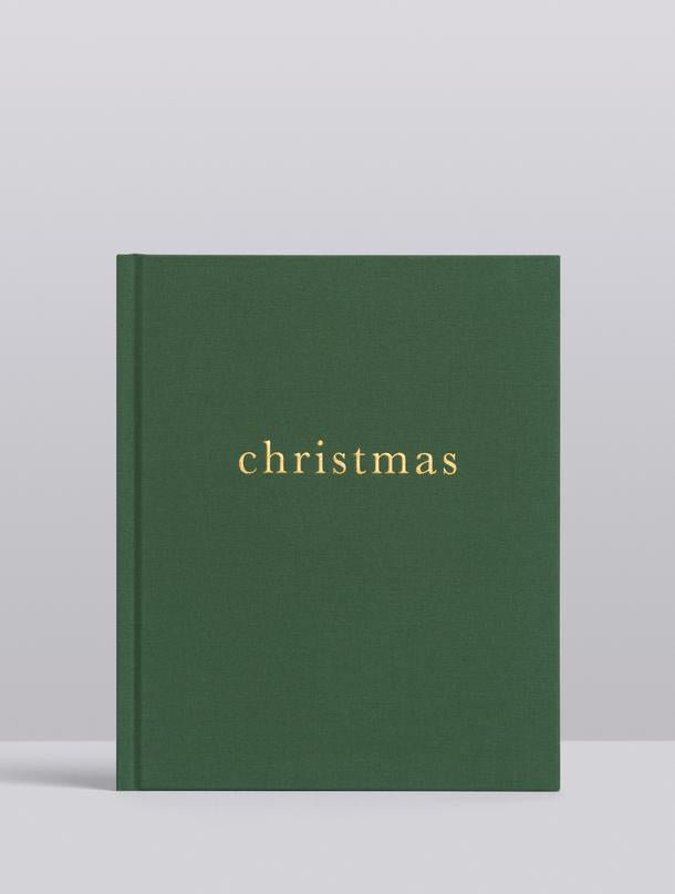 Forest green linen Christmas family book with gold foil title, on grey