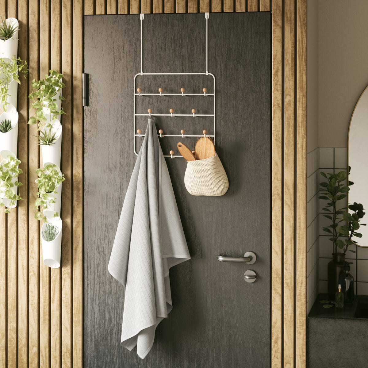 Umbra Estique organiser in white on a dark timber door with a towel and bag hanging