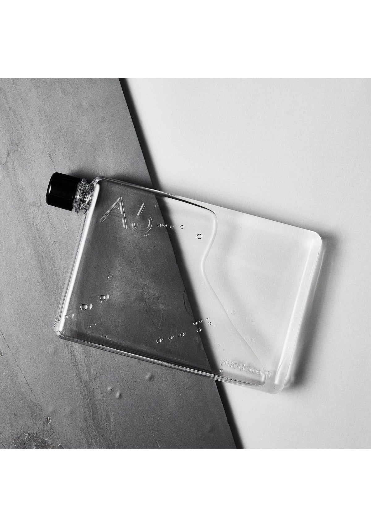 A clear A5 Memobottle emphasizing daily water intake, resting on a white surface.