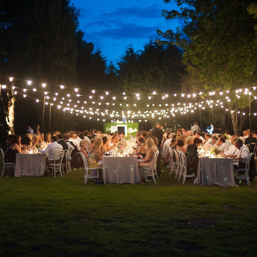 Festoon lights with clear bulbs strung between posts at dusk