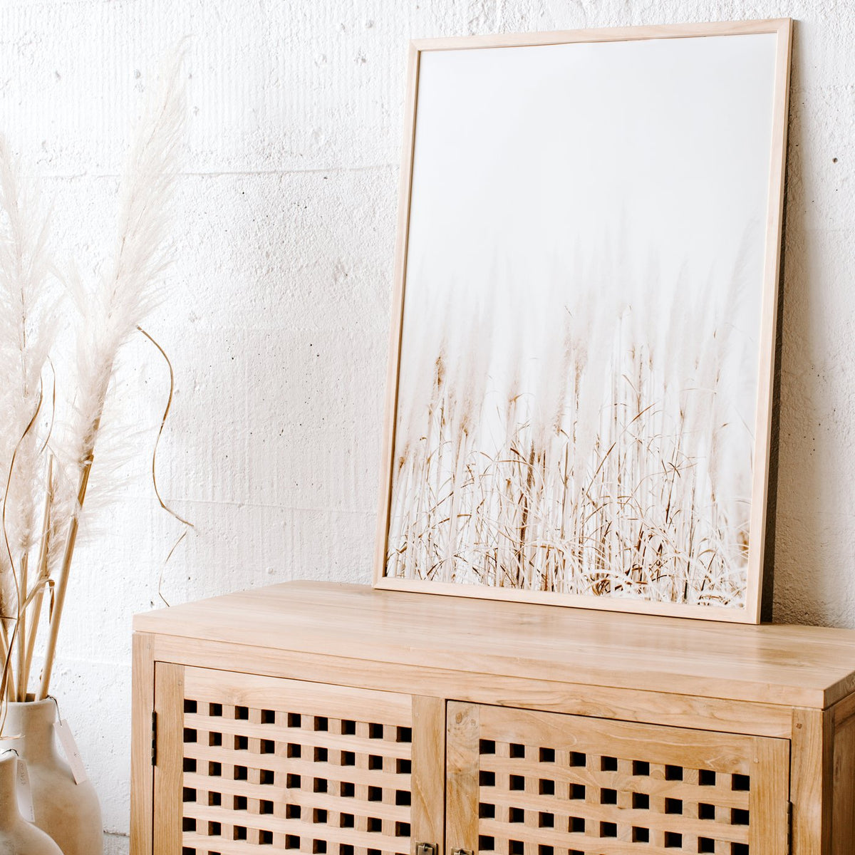 Pampas print in a timber frame on a timber cabinet beside dried pampas