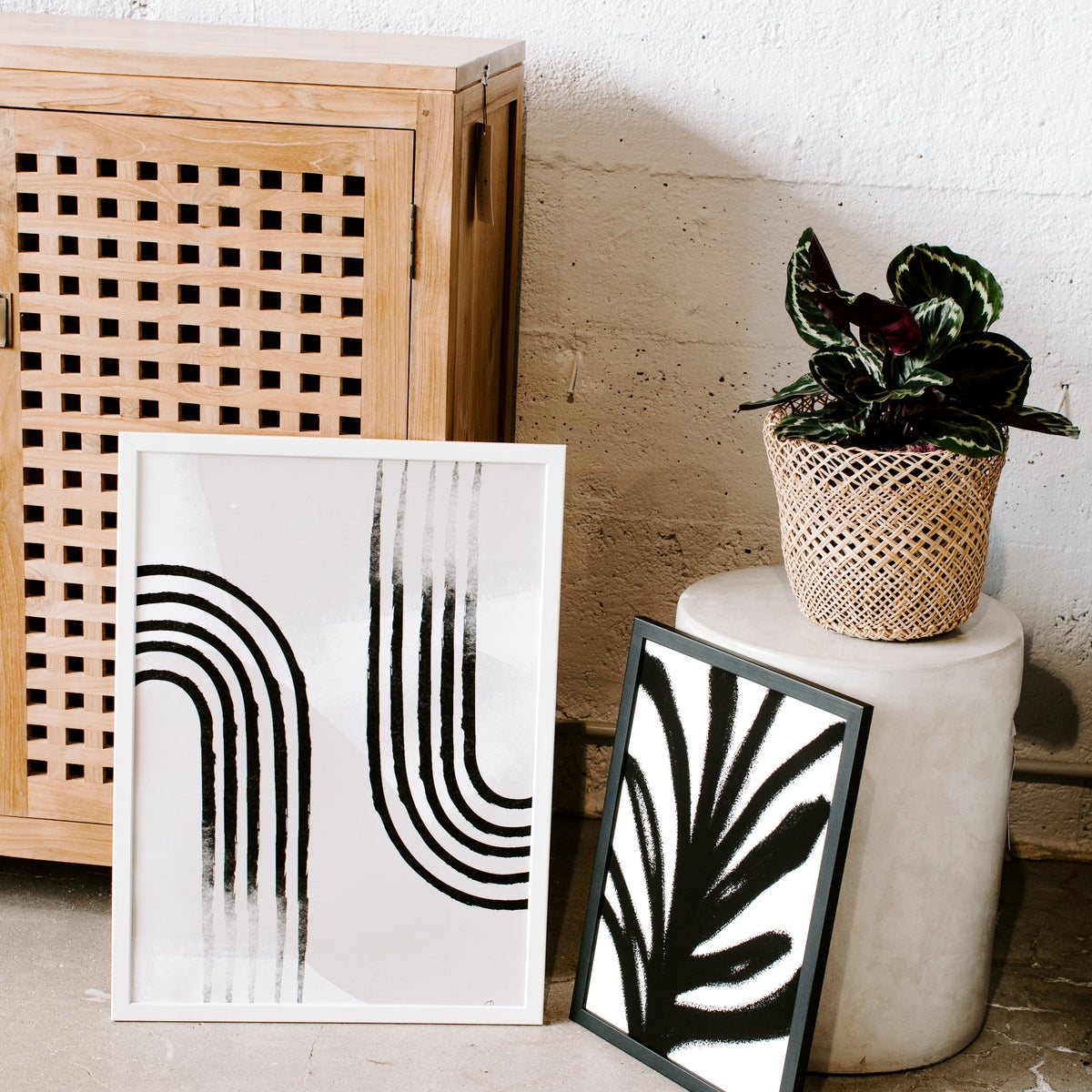 Curve Line No. 3 print on the floor beside a cane cabinet and a plant on a stool