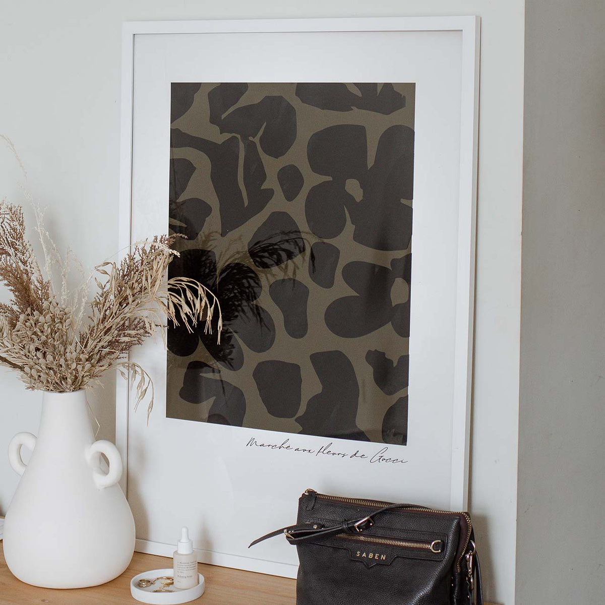Flower Market Khaki print in a white frame beside dried grass in a white jug
