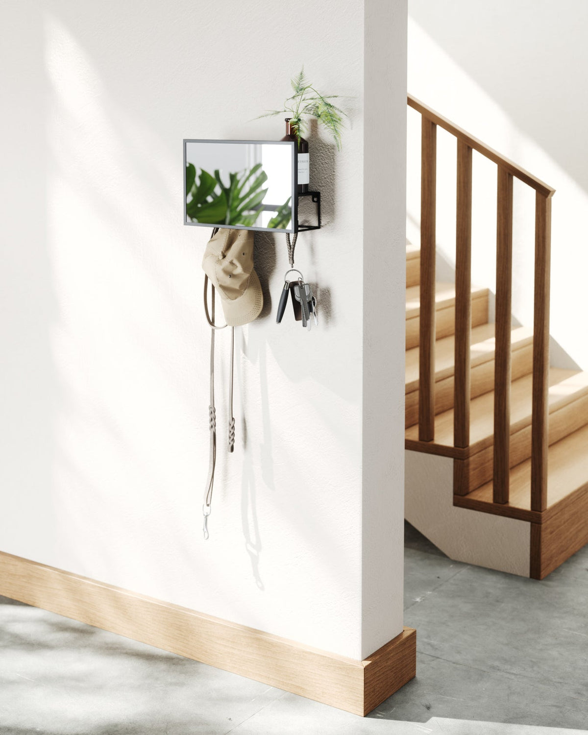 Black Umbra Cubiko mirror and organiser mounted on a wall beside a trailing plant.