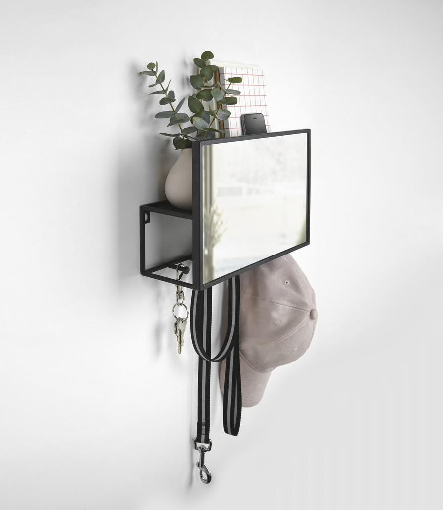Umbra Cubiko organiser in black hung on a hallway wall next to a plant.