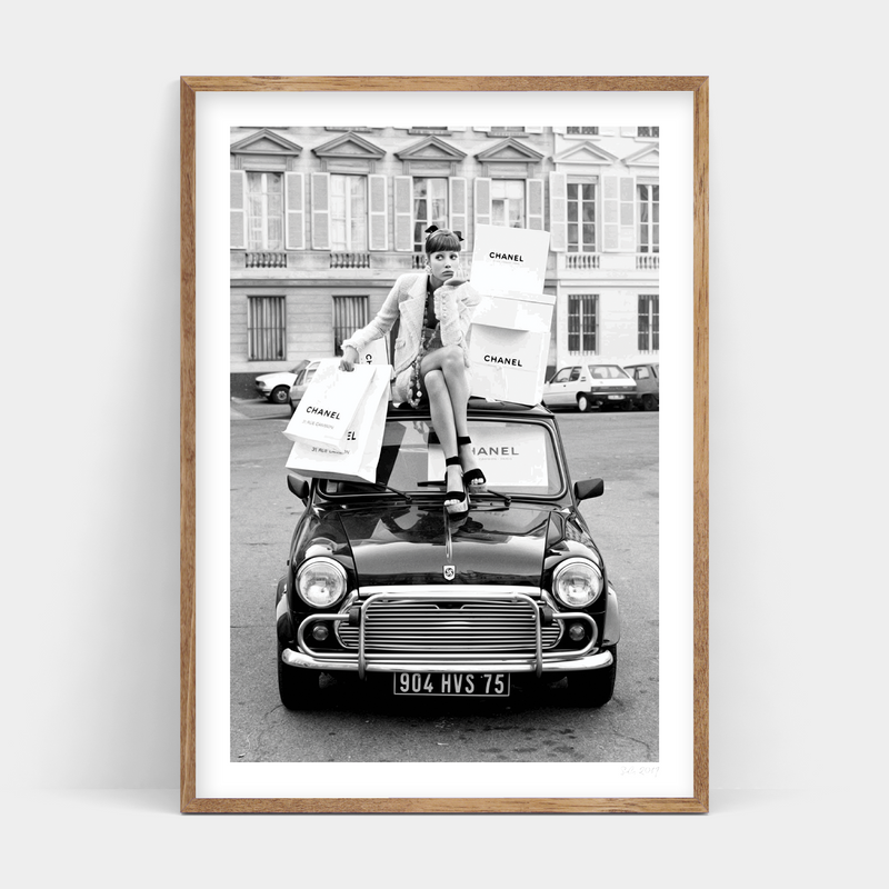 A black and white photo of a woman sitting on top of a mini cooper, available for RETAIL THERAPY prints by Art Prints.