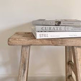 A wooden stool with Calm | Interiors to Nurture, Relax and Restore | Sally Denning books on top of it.