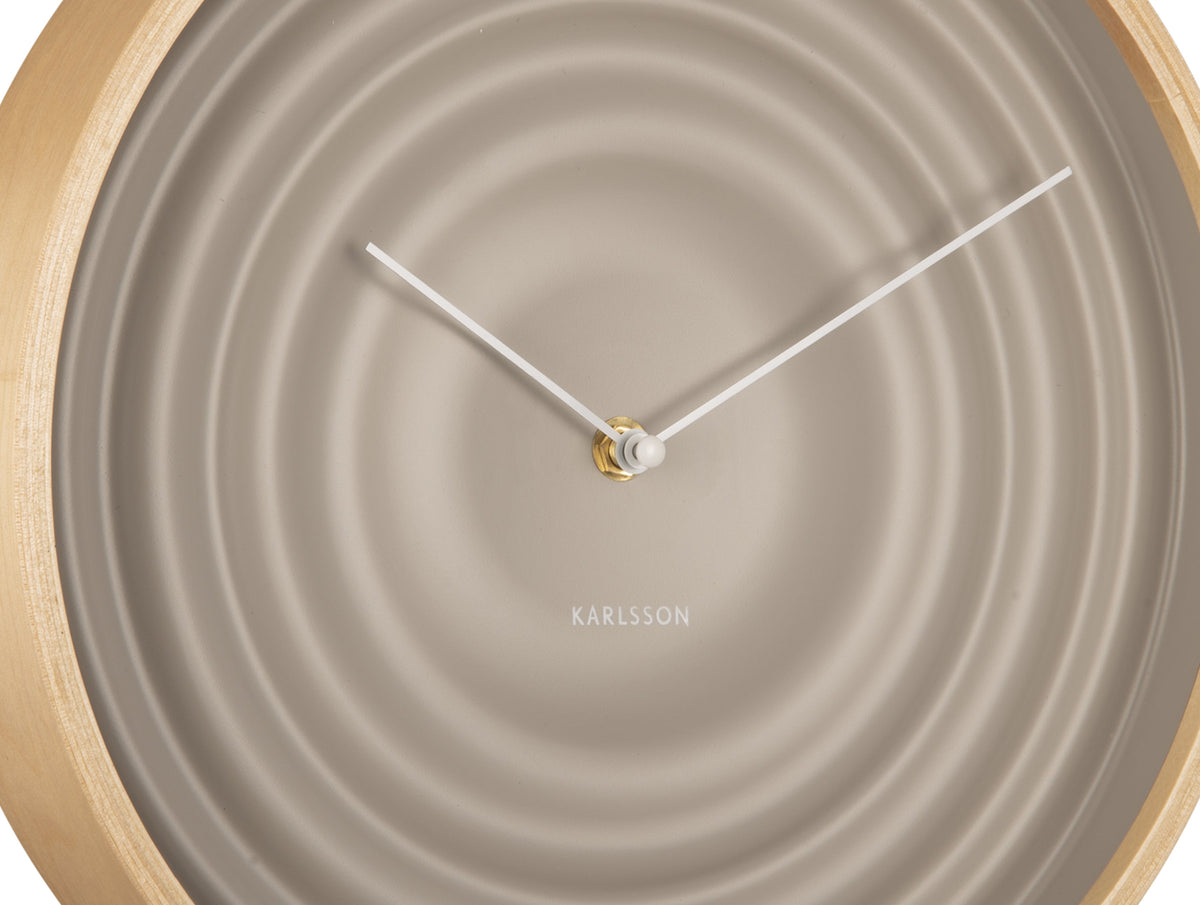 Close view of the grey clock face showing the rippled rings and pale hands