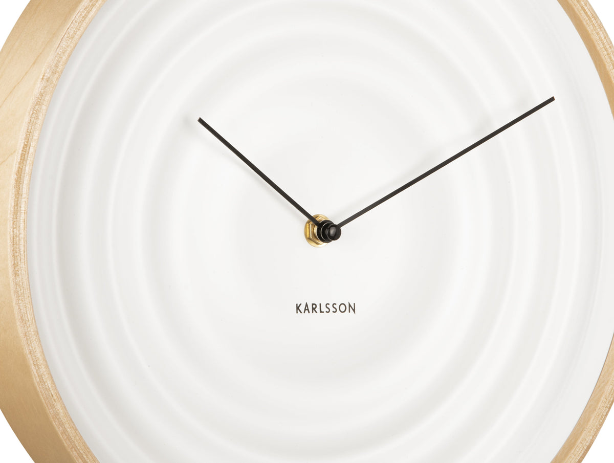 Close view of the white clock face showing the rippled rings and black hands