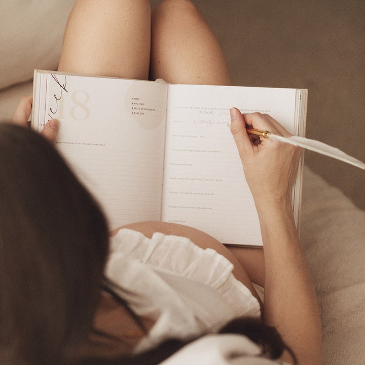 A pregnant woman documenting her journey in the Becoming MAMA - A Pregnancy Journal, a thoughtful gift for expectant mothers.