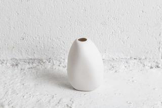 Single white Harmie Vase Pipi on a textured white concrete ledge