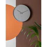 Aesthetic Karlsson clock on a minimal wall next to a plant.