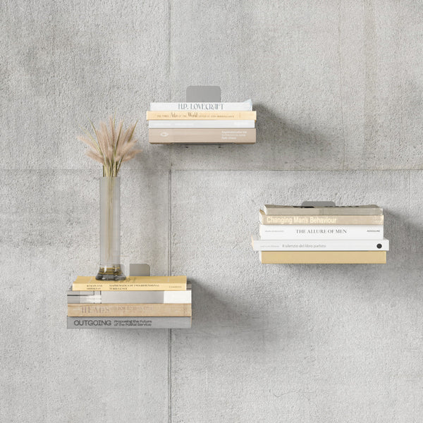 Three Umbra Conceal 3 Pack - Silver invisible book shelves on a concrete wall.