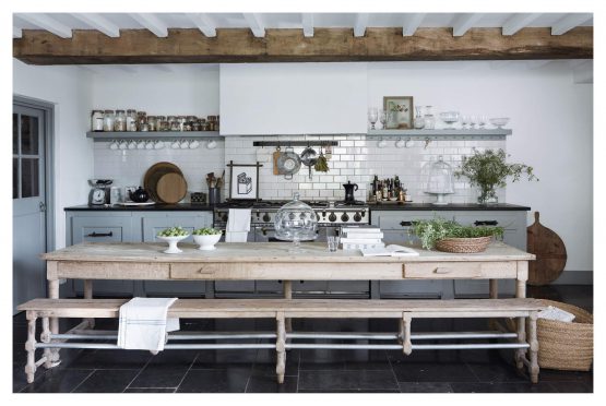 A kitchen with "For The Love Of White: The White & Neutral Home" books placed on a wooden bench and wooden beams.