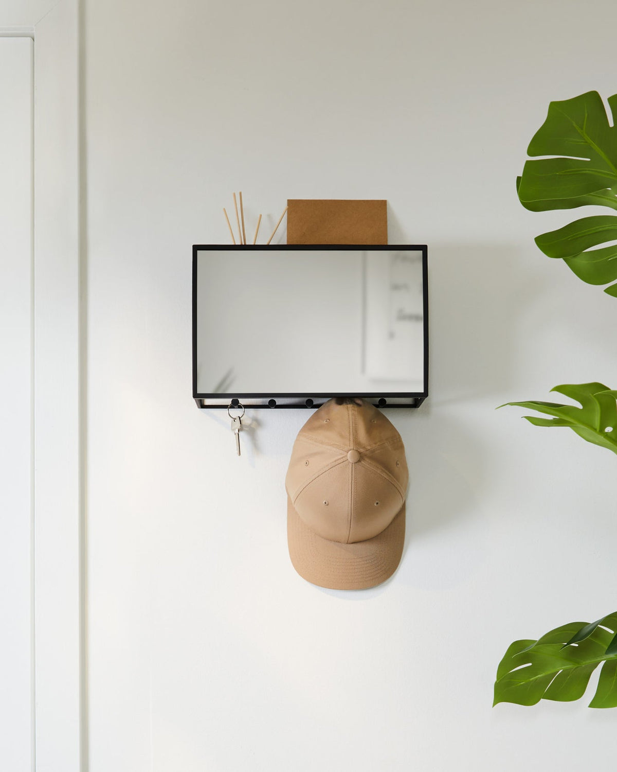 Umbra Cubiko entryway organiser in black with a hat hanging from one of its five hooks.