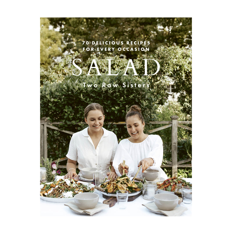 Two women are sitting at a table and eating a salad from the brand "Books," which offers 70 delicious recipes for every occasion.