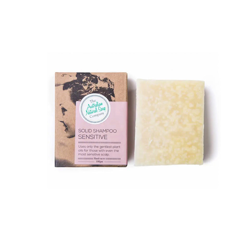 Sensitive solid shampoo bar beside its kraft carton on a plain background
