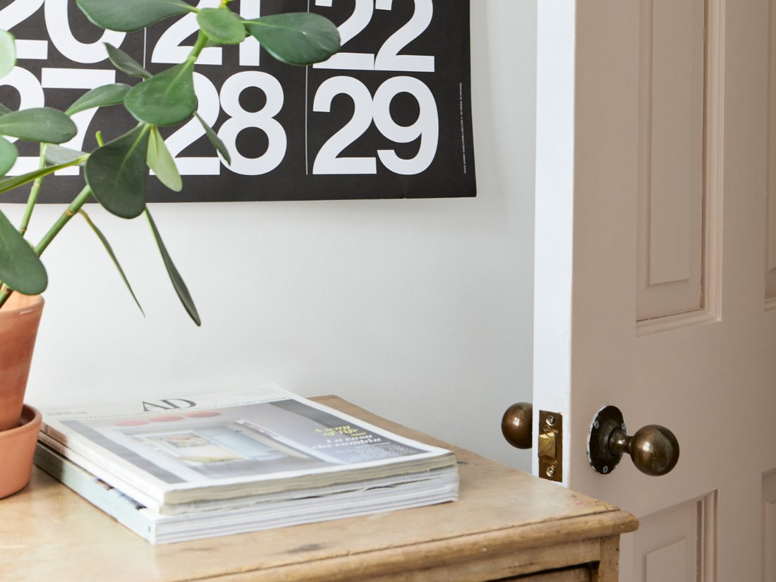 Stendig Calendar hung above a shelf of books and a vase in a minimal room