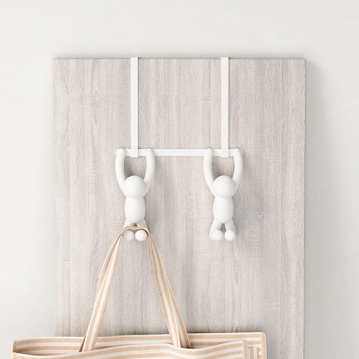 Umbra Buddy over-the-door hook in white holding a bag