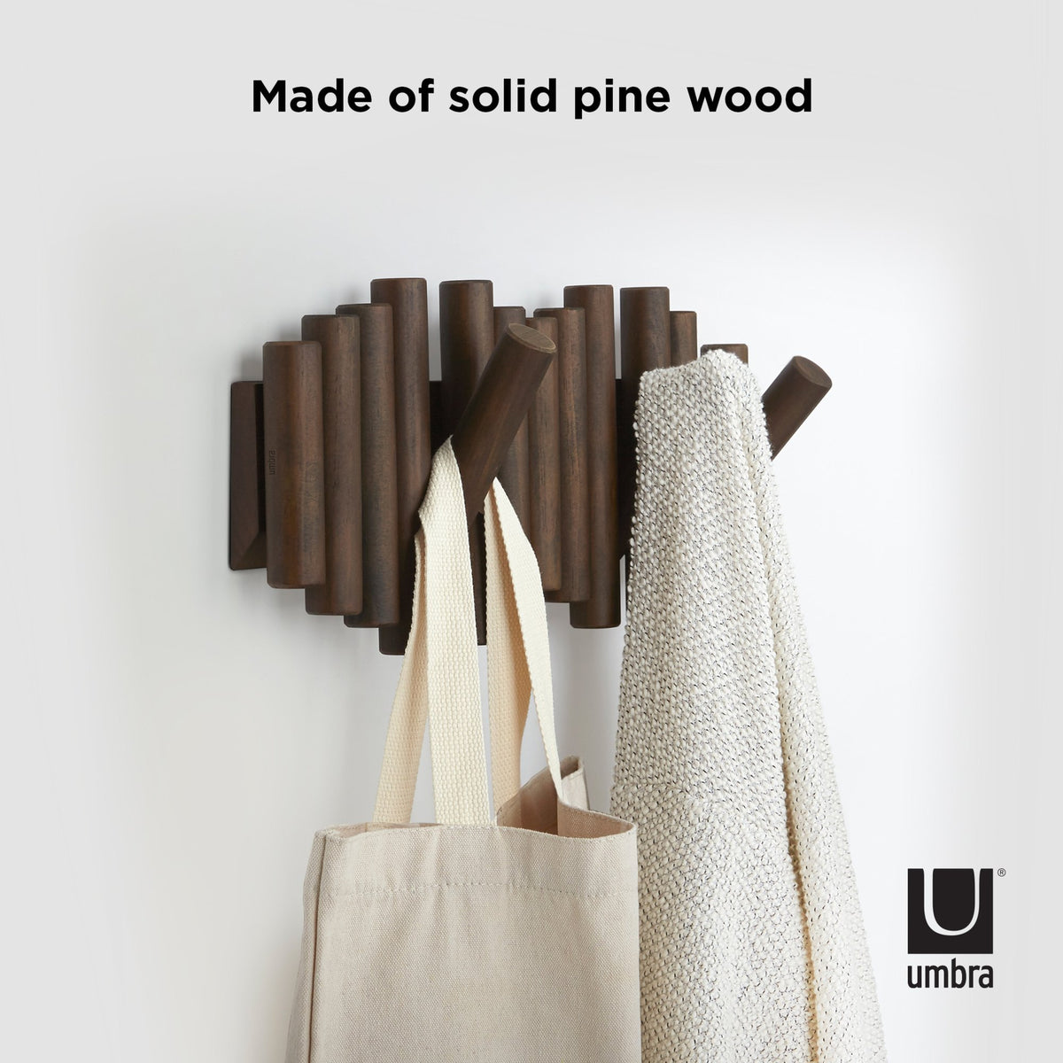 Umbra Picket rail wall hook in solid pine stained walnut, holding a tote and throw