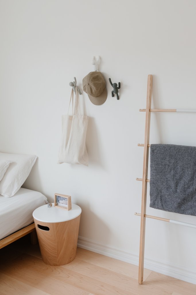 Umbra Buddy hooks in a bedroom holding a hat and tote bag beside a ladder rail