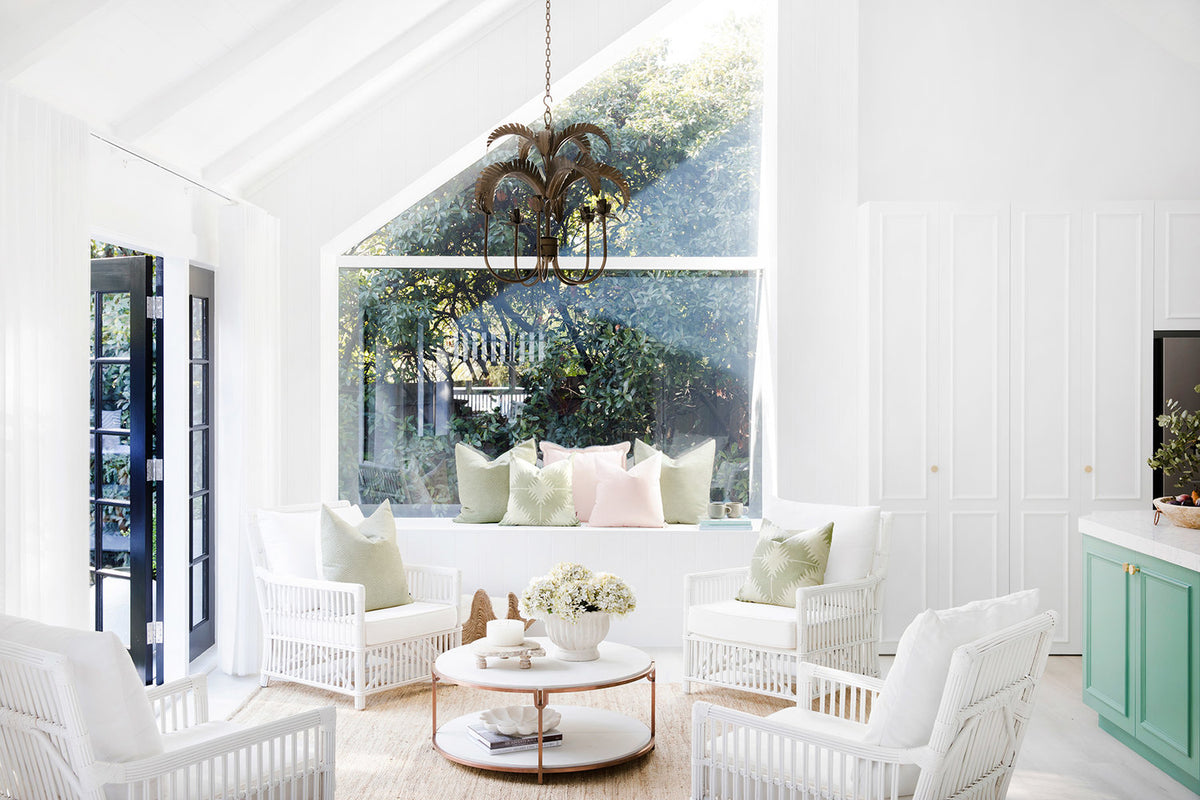 White living room with sofas and a tall window to palm trees
