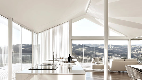 Sun-drenched modern interior with vaulted ceilings, sheer white curtains, and expansive glass windows framing a serene rural landscape—an architectural space designed to evoke awe through height, light, and stillness.