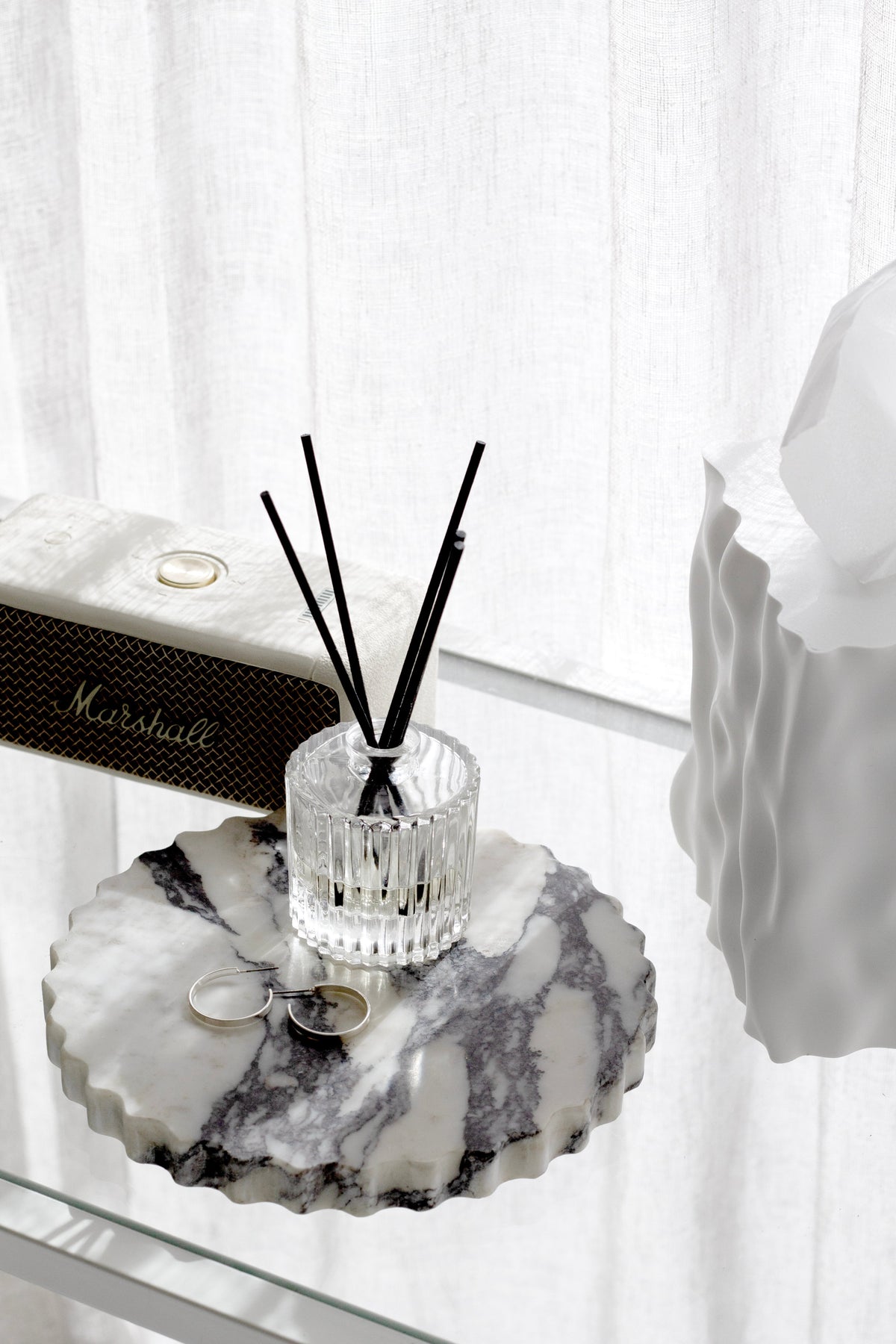 Ecoya Celebration reed diffuser on a scalloped marble tray by a window with sheer curtains