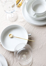 A set of Zakkia handmade Muddling Spoon - Brass / Silver silverware and Zakkia food-grade compliant white plates on a table.