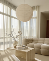White linen pendant light shade hanging in a bright living space with soft natural light, a boucle sofa, and neutral decor for a calming, organic feel.